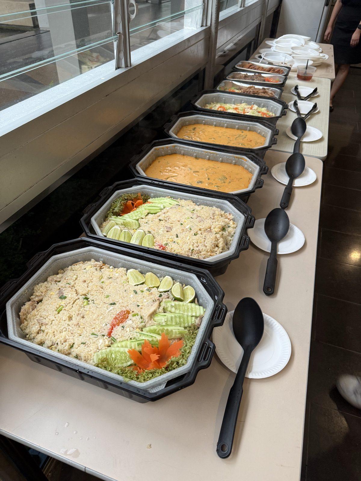 A line of self-heating trays with serving spoons along a restaurant counter