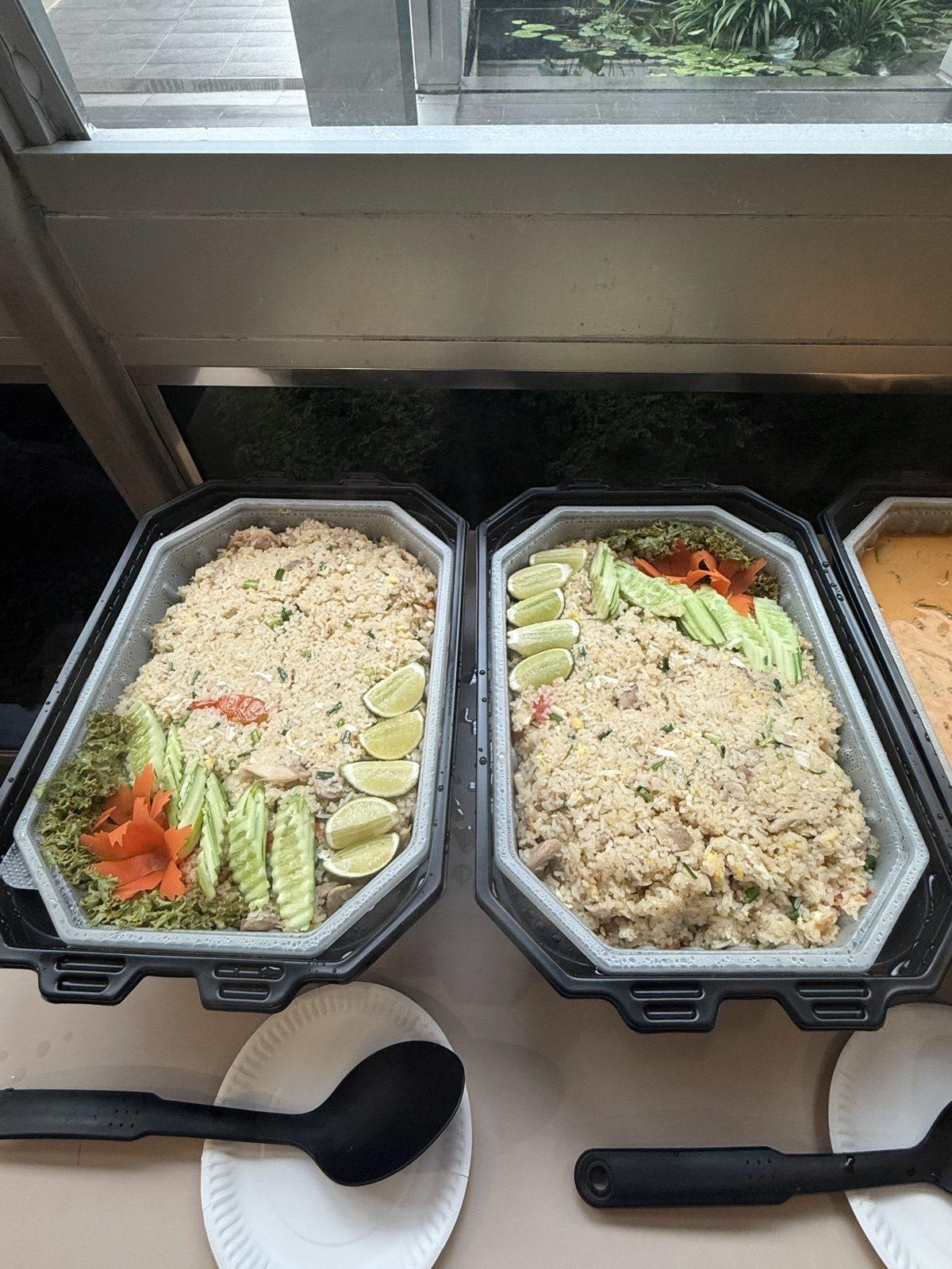 Two self-heating trays of fried rice garnished with cucumber and chilli